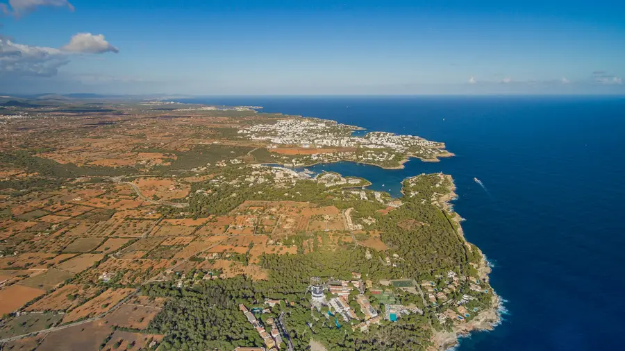 Luftbild der Küste von Cala d'Or mit der weiß bebauten Siedlung und dem Hafen in der Cala Llonga