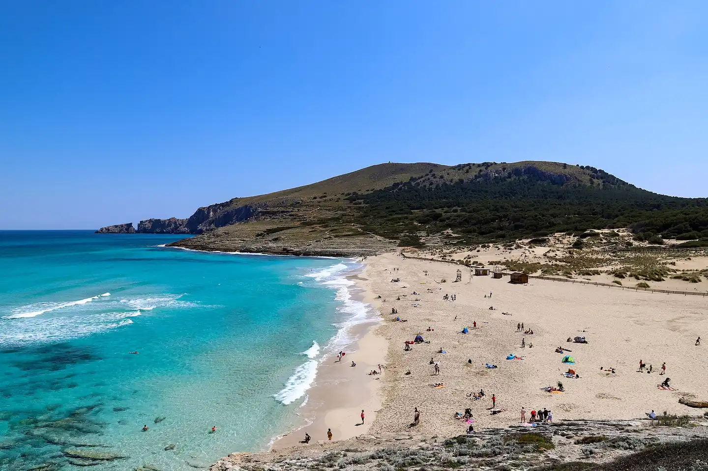 Die weite Bucht von Cala Mesquida mit türkisfarbenem Wasser und den geschützten Dünen, dahinter die Talaia de Son Jaumell