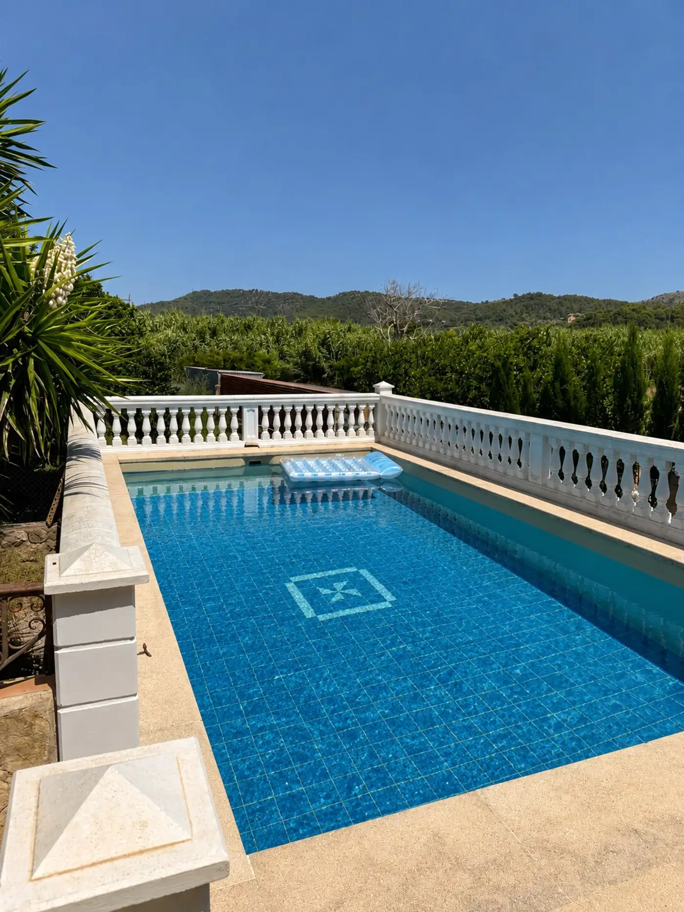 Pool mit gemauerter Balustrade, dahinter Felder und die Hügel des Ostens