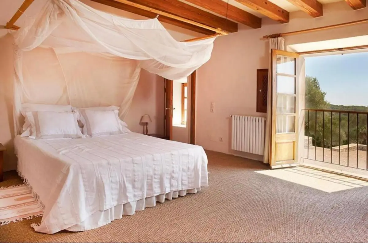 Schlafzimmer mit Himmelbett und Flügeltür auf den Balkon