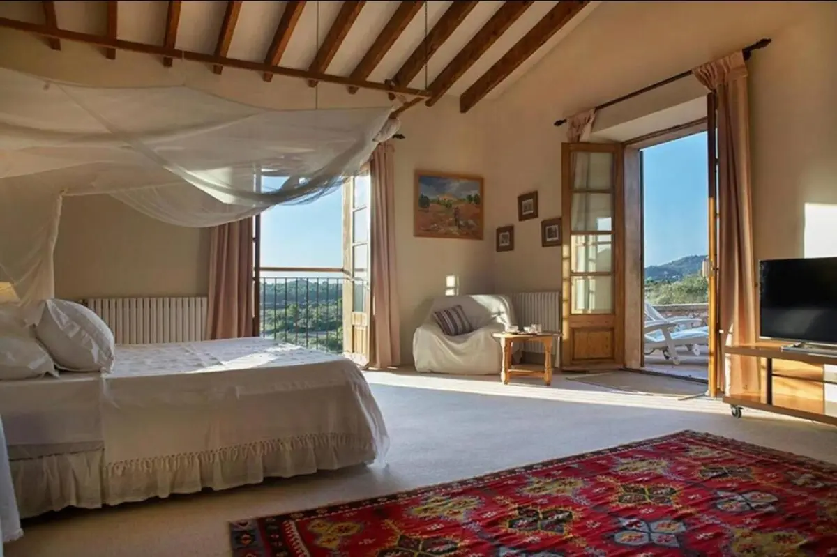 Schlafzimmer mit Himmelbett und Flügeltüren auf die Terrasse