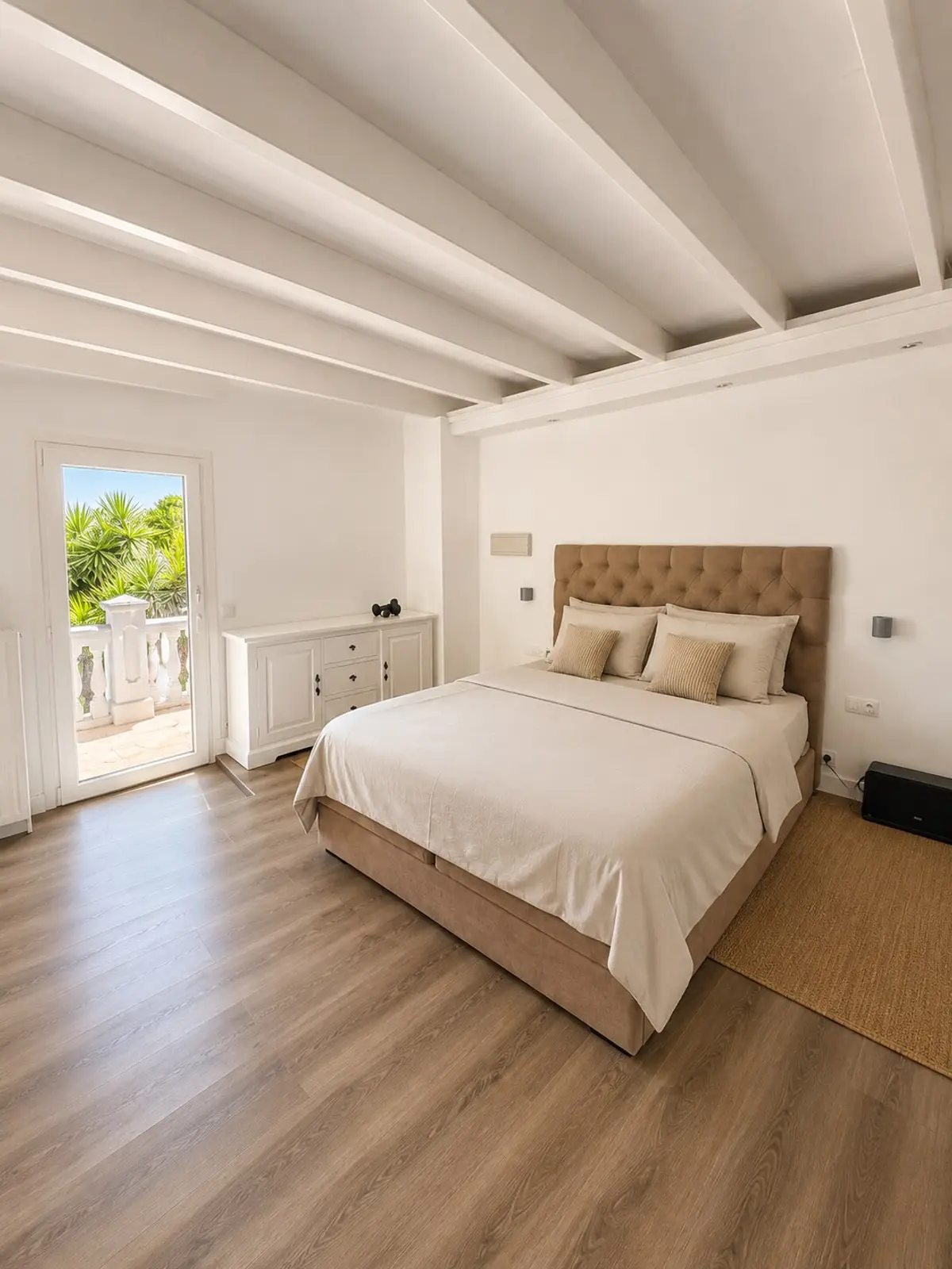 Schlafzimmer mit gepolstertem Kopfteil, Holzboden und offener Balkendecke