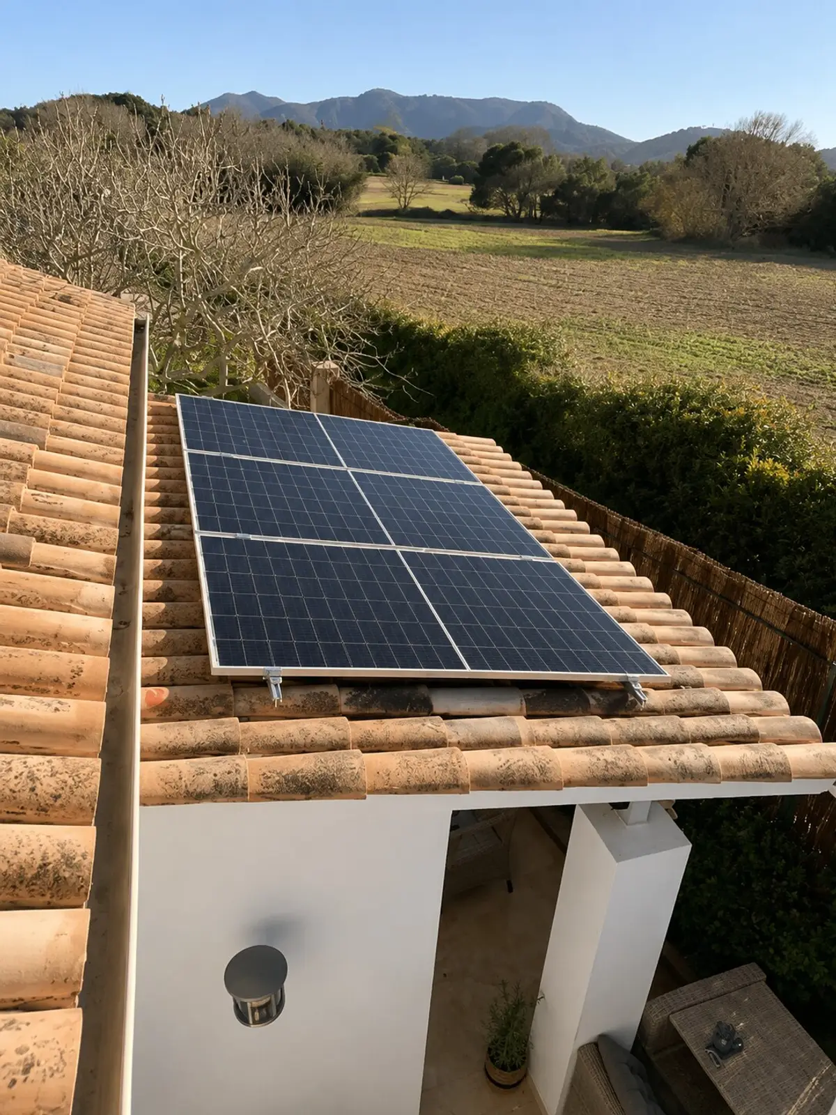 Solarmodule auf dem Ziegeldach, dahinter Felder und Hügel