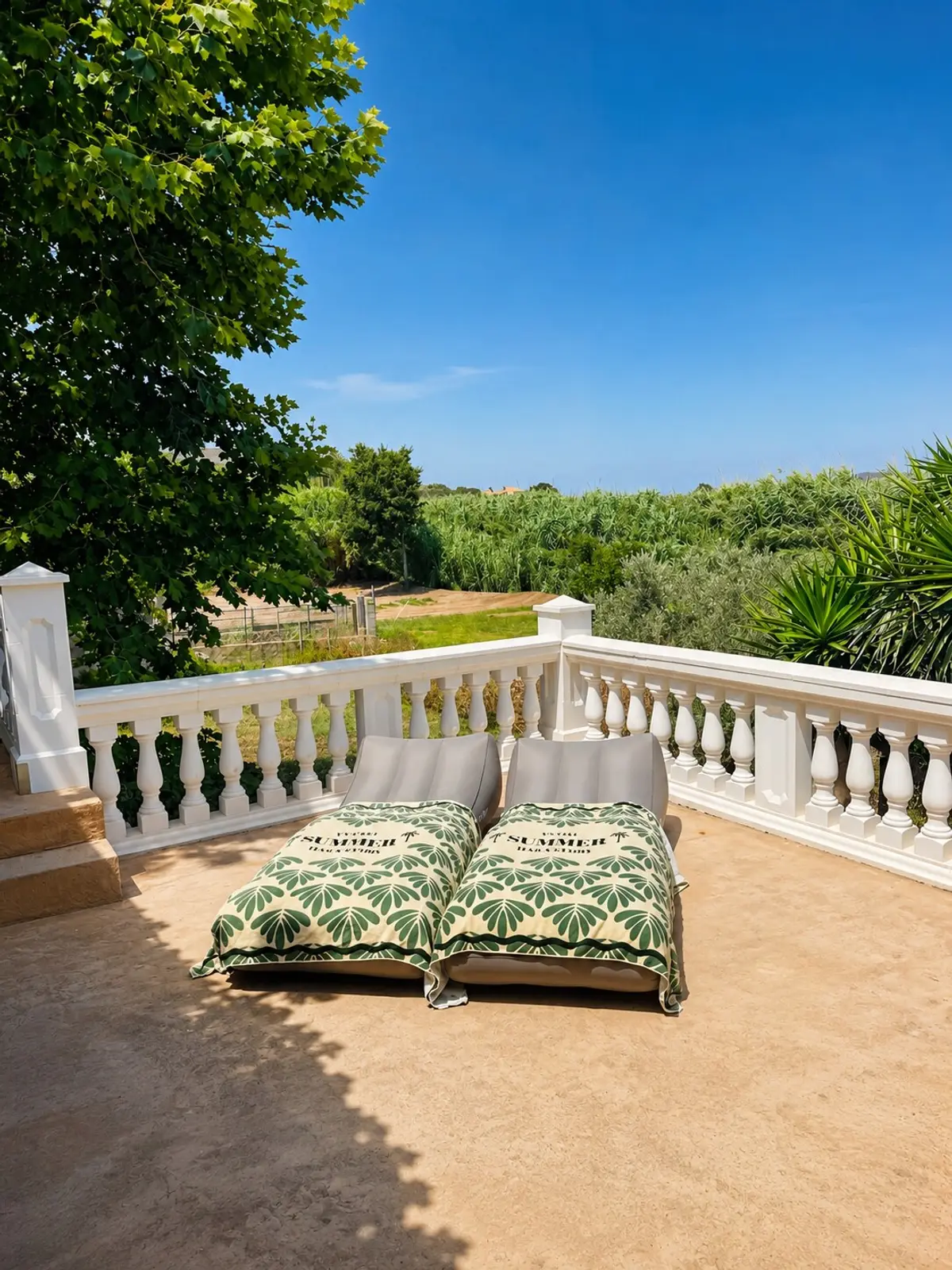 Terrasse mit Kissen auf der Balustrade, Blick über Bäume und Felder