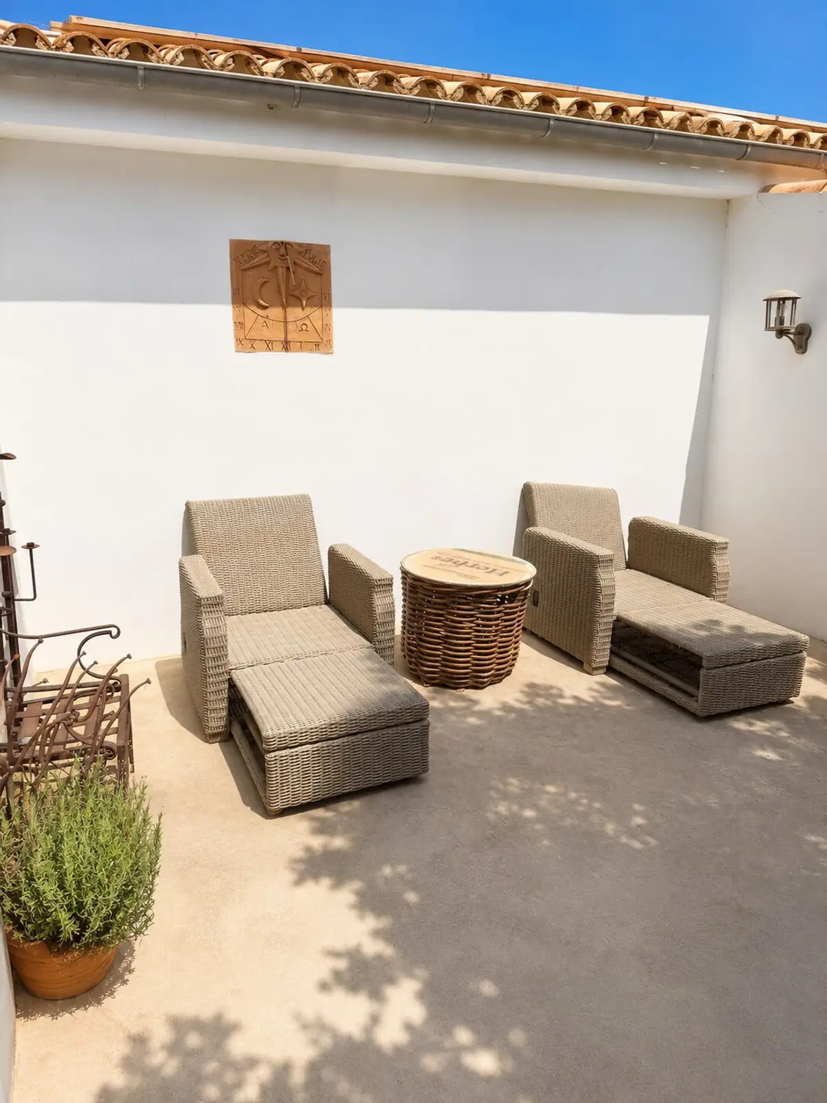 Sonnenliegen aus Rattan auf der Terrasse an der weißen Hauswand